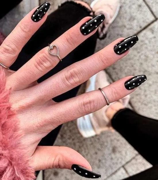 Unhas pretas com bolinhas brancas.