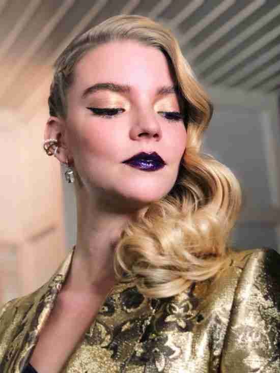 Batom roxo com sombra dourada.