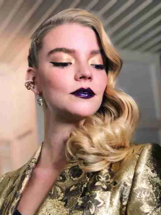 Batom roxo com sombra dourada.