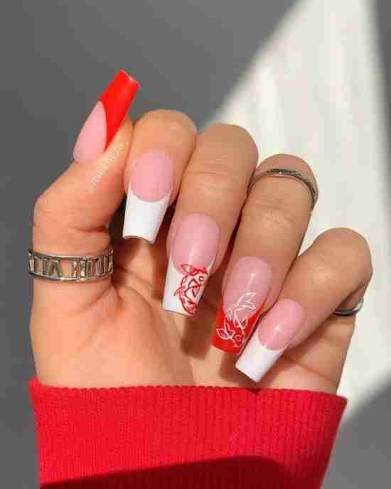 Unhas decoradas vermelhas com branco.