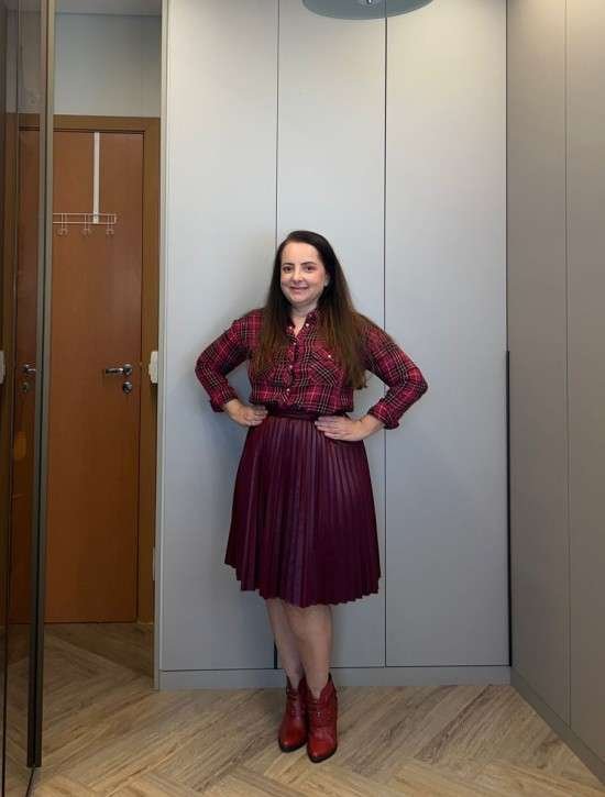 Look com camisa xadrez e saia plissada.
