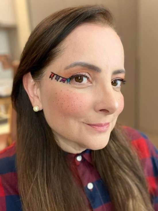 Maquiagem para festa junina com bandeirinhas no rosto e sardas fake.